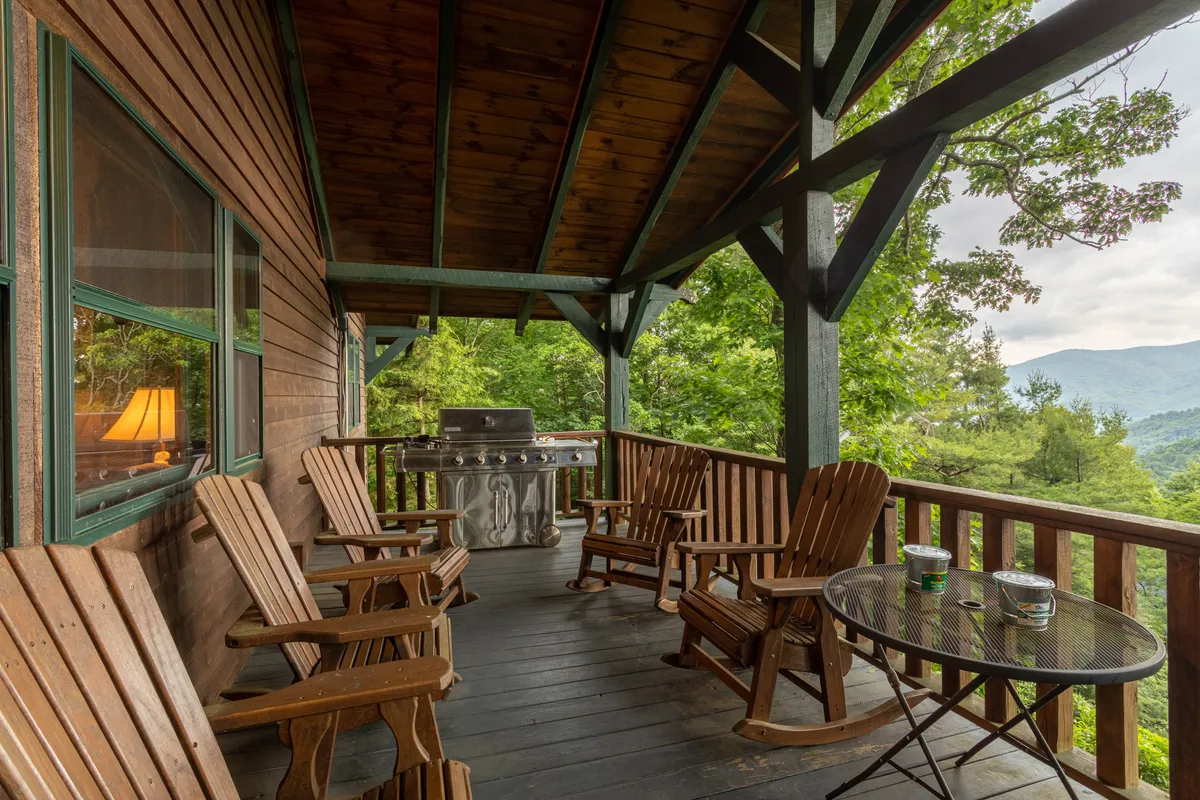 An inviting deck with rocking chairs and a grill overlooks stunning mountain views. The outdoor area is open and not fully enclosed, aligning with the section’s advice about pet supervision and mountain adventure atmosphere.